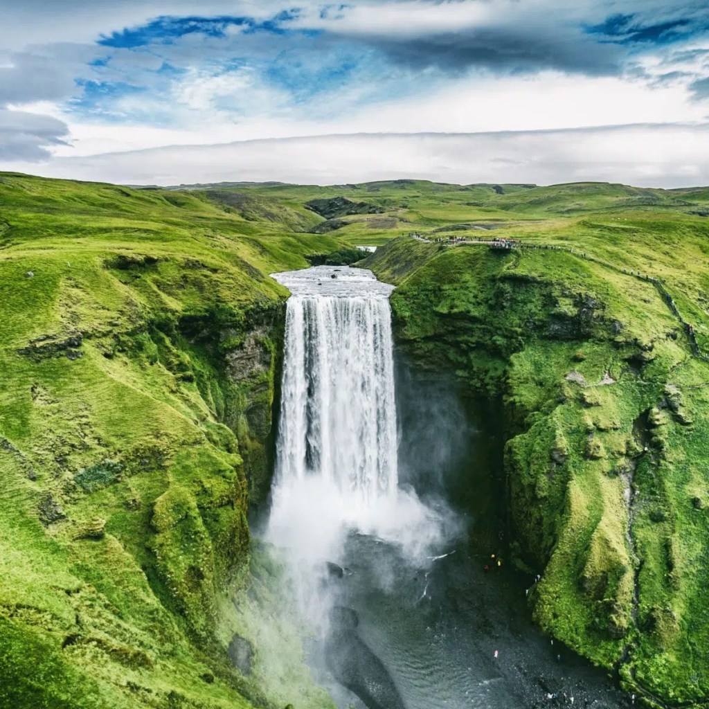 A waterfall descending through a green landscape.