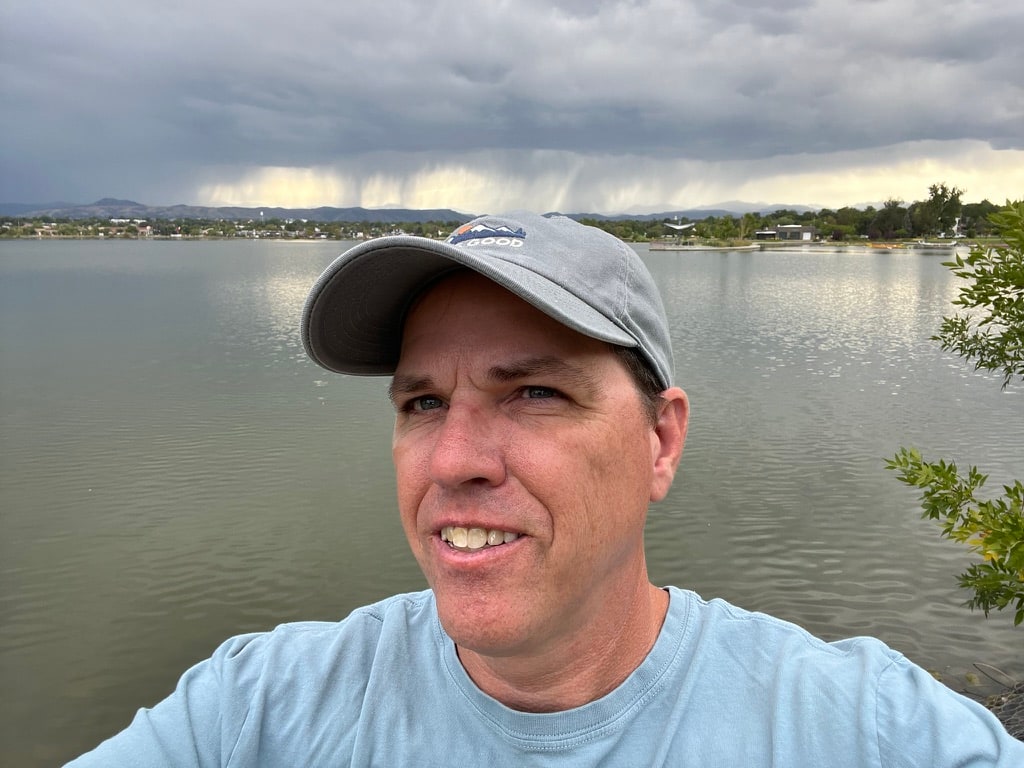 Phillip beside a lake beneath an approaching summer storm.