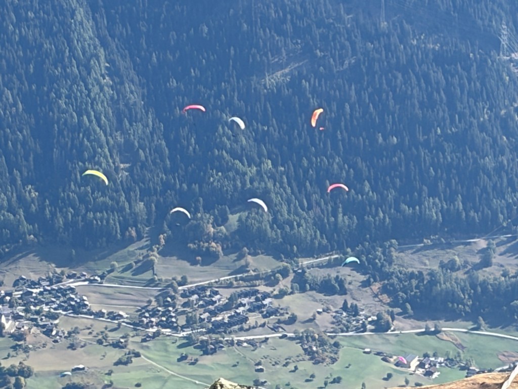 Colorful paragliders above the valley near Fiesch.