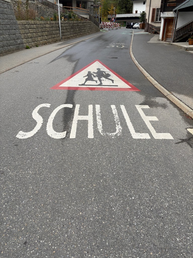 School crossing symbol and SCHULE painted on a village street.