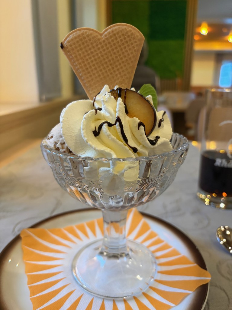 Ice cream sundae topped with chocolate sauce and a heart-shaped wafer.