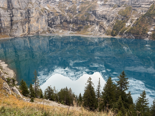 Blue lake reflecting cliffs and autumn woodland