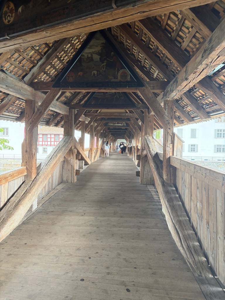 Timber beams and painted triangular panels frame the walkway through Spreuerbrücke.
