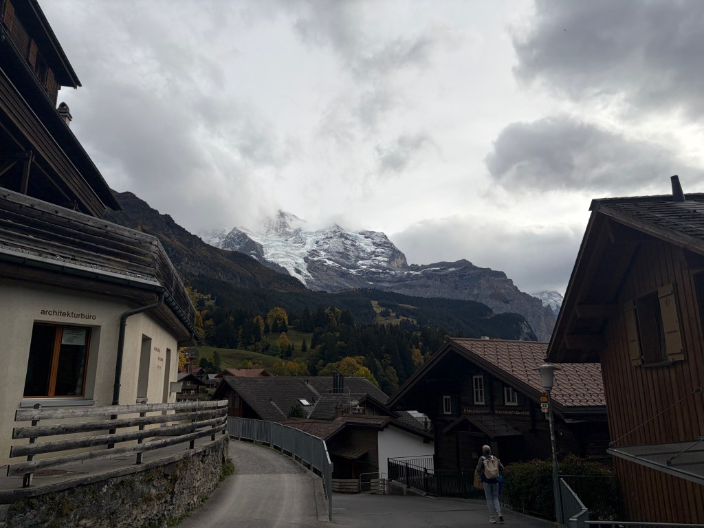 Wengen village lane and chalets beneath cloud-covered mountain peaks.