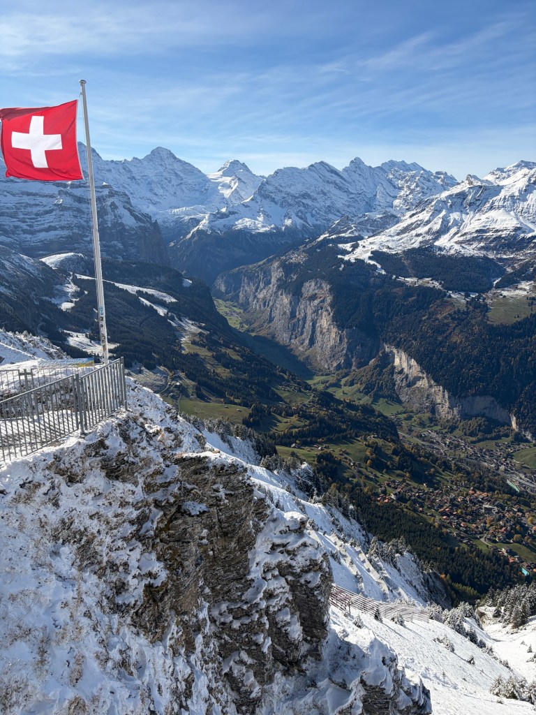 Swiss flag above snowy slopes overlooking Lauterbrunnen valley.