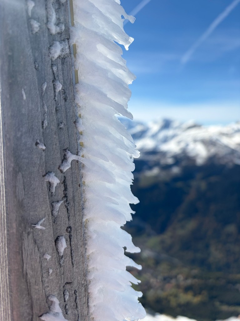 White ice crystals projecting from a post against a blue sky.