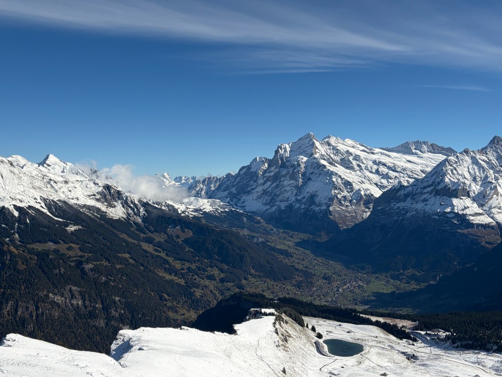 Snow-capped peaks beneath blue sky and wispy clouds.